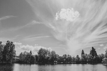 Reflejo Lago con barcas arboles y cielo azul con nubes blanco y negro