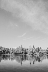 Reflejo Lago con barcas arboles y cielo azul con nubes blanco y negro 
