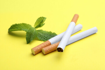 Menthol cigarettes and mint on yellow background