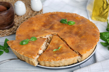 Delicious meat pie with basil on white table, closeup