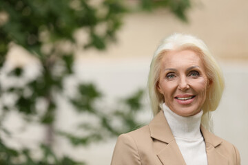 Portrait of happy mature woman outdoors. Space for text