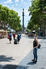 Young girl with a mask on the Ramblas of Barcelona, ​​in the background you can see the statue of Cristobal Clon
