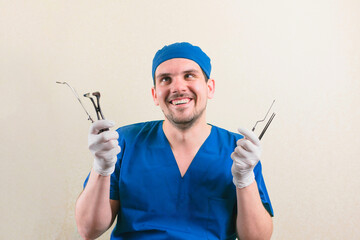 Young smiling doctor with medical instruments in his hand in green surgeon suit isolated