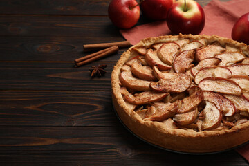 Delicious apple pie and ingredients on wooden table, space for text