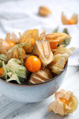 Ripe physalis fruits with dry husk on white wooden table, closeup