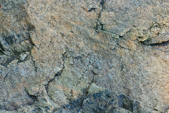 Cracked granite stone texture. Solid rock close-up. Weathered rock