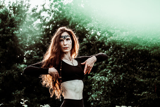 Beautiful caucasian woman with long brown hair, wearing black clothes with bare stomach portrait in forest