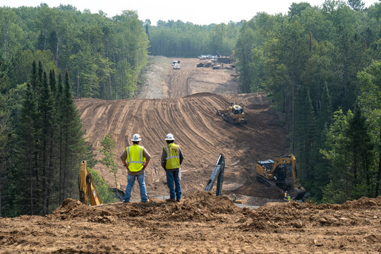 CASS CO, MN - 6 AUG 2021: Enbridge Line 3 Oil Pipeline Construction Site in Minnesota forest with excavators and bulldozers covering the installed pipe. Foreground is intentionally out of focus.