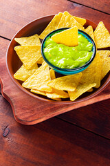 Guacamole sauce and tortilla chips. Bowl with guacamole and nachos on wooden boards. Copy space
