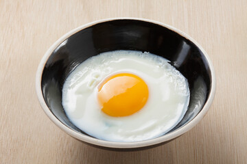 fried egg in a ceramic bowl on wooden background