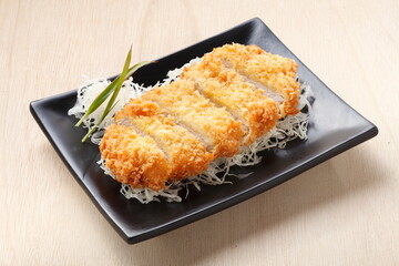 Japanese food, Tonkatsu pork deep fried with bread crumbs cutlet on top of sliced cabage on wooden, background.