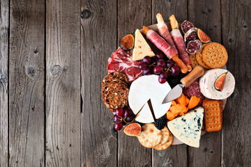 Charcuterie board of a selection of meats, cheeses and appetizers. Overhead view on a dark wood...