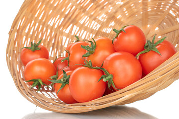Several red organic tomatoes in a straw bowl, close-up, isolated on white.
