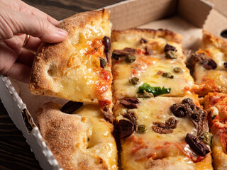 Woman take piece of Fresh baked traditional italian pizza Alla Puttanesca