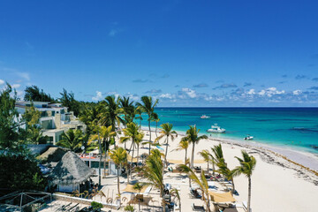 Obraz premium Caribbean sea coastline with Speed boat floating along tropical island with palm trees. Dominican Republic. Aerial view