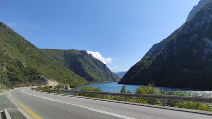 The river Neretva flows between the mountains along the road, one sunny day in October.