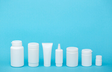 White different medical or cosmetic jars on a blue background as a concept of cosmetology of medecine and treatment