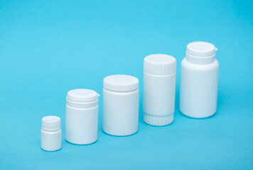 White different medical or cosmetic jars on a blue background as a concept of cosmetology of medecine and treatment