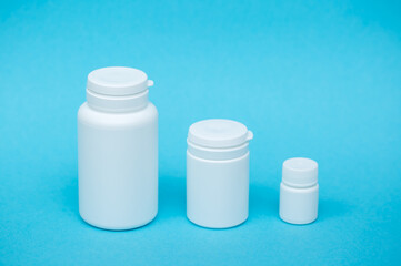 White different medical or cosmetic jars on a blue background as a concept of cosmetology of medecine and treatment