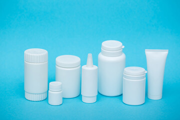 White different medical or cosmetic jars on a blue background as a concept of cosmetology of medecine and treatment