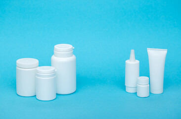 White different medical or cosmetic jars on a blue background as a concept of cosmetology of medecine and treatment