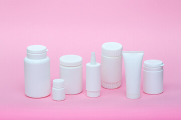 White different medecine or cosmetic jars on a pink background as a concept of cosmetology of medecine and treatment