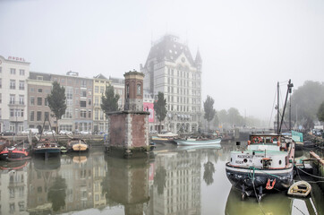Fototapeta na wymiar Rotterdam, The Netherlands, October 8, 2021: Wijnhaven harbour with historic vessels and the famous White House on a somewhat foggy day