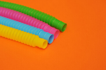 Colorful trendy toys pop tube on orange background