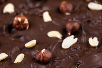 chocolate background with peanuts and hazelnuts close-up, side view