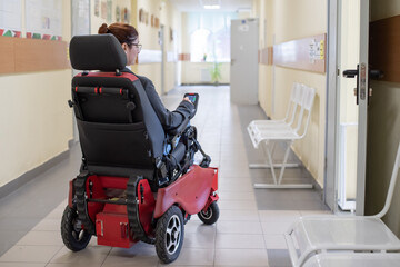 Caucasian woman in electric wheelchair in university corridor.