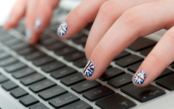 young girl typing on computer keyboard with union jack finger nails
