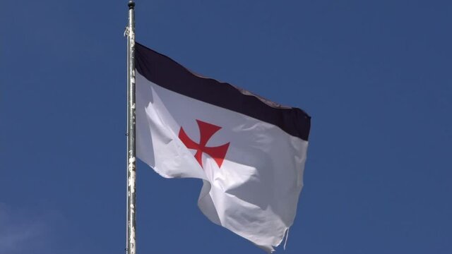 Slow Motion of flag banner the knights templars at castle medieval in Jerez de los Caballeros Spain. The Catholic military order was a poor fellow soldiers of christ and temple of solomon. -Dan
