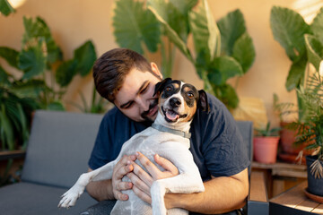 Young man holding his dog with a funny face and playing with him