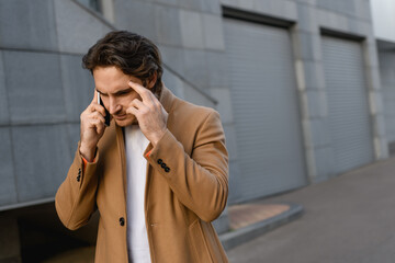 Concentrated businessman talking on smartphone on urban street 