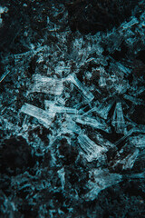 macro close up of frozen needle ice with dark moody background. Ice on the ground with rocks in the...