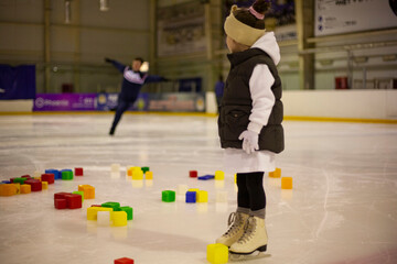 Little girl learns to skate. Children's skates. A child training on ice. The concept of children's figure skating. Children's sports. Winter sport