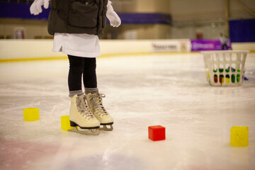 Little girl learns to skate. Children's skates. A child training on ice. The concept of children's figure skating. Children's sports. Winter sport