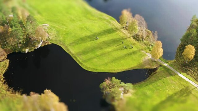 Cinematic aerial footage over colorful green golf course - few unidentified people