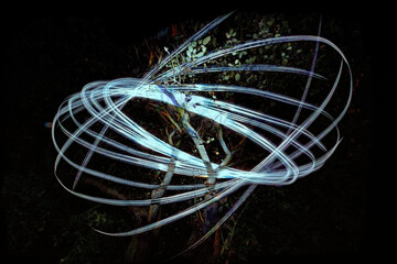 Light painting as spiral light traces in front of a tree at night, alienated double exposure,...