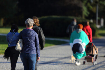 Kobieta z torebką spaceruje w parku. - obrazy, fototapety, plakaty