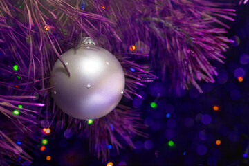 Christmas decoration ball on a pine branch in purple tones