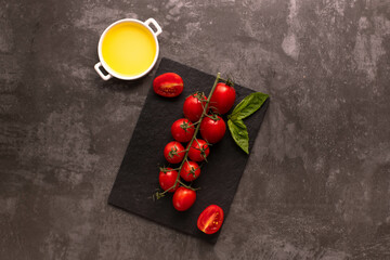 Naklejka na ściany i meble Red juicy cherry tomatoes on black board with olive oil. Copy space.