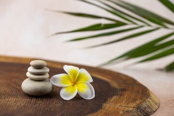 Obraz na płótnie Canvas Pyramids of gray and white zen pebble meditation stones on beige background with plumeria tropical flower. Concept of harmony, balance and meditation, spa, massage, relax