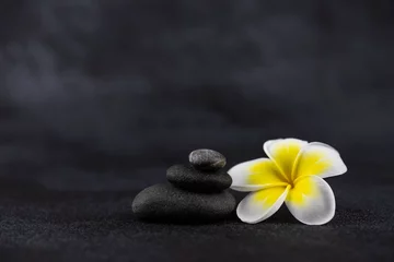Foto op Canvas Piramides van grijze en witte zen pebble meditatie stenen op zwarte achtergrond met plumeria tropische bloem. Concept van harmonie, balans en meditatie, spa, massage, relax © strigana