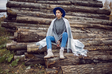 woman director is standing by a log at a sawmill in a scarf and a blue hat