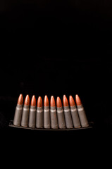 front view, close distance of ten 7.62.mm rifle shells of a metal stripper clip, on a black background