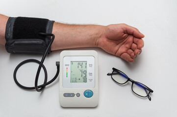 The person measures their own blood pressure at the medical table. Taking care of your own health