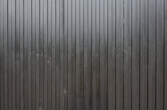 black corrugated metal surface. real image of a used gate. industrial style background.