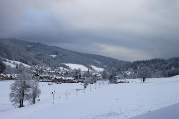 a village under the snow. A view from a valley to the mountains under the snow, it's cold and gray, it's winter.
