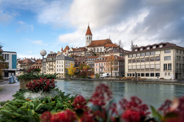 Fototapeta premium Colorful view of Aare river promenade and Thun Skyline with Thun City Church (Stadtkirche) and Thun Castle - Thun, Switzerland